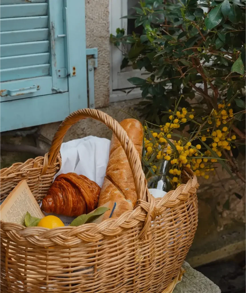Panier en osier tressé garni de pains, devant des volets bleus
